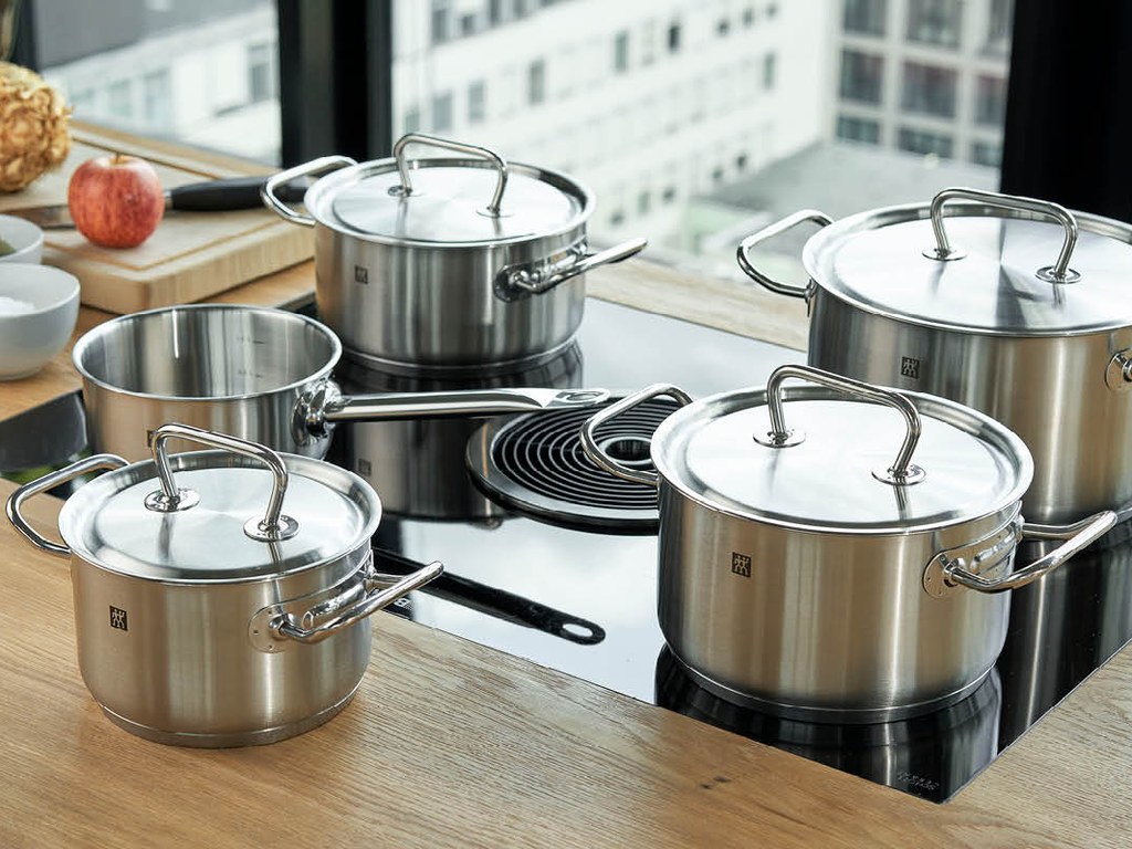 A complete stainless steel cookware set arranged on a kitchen counter