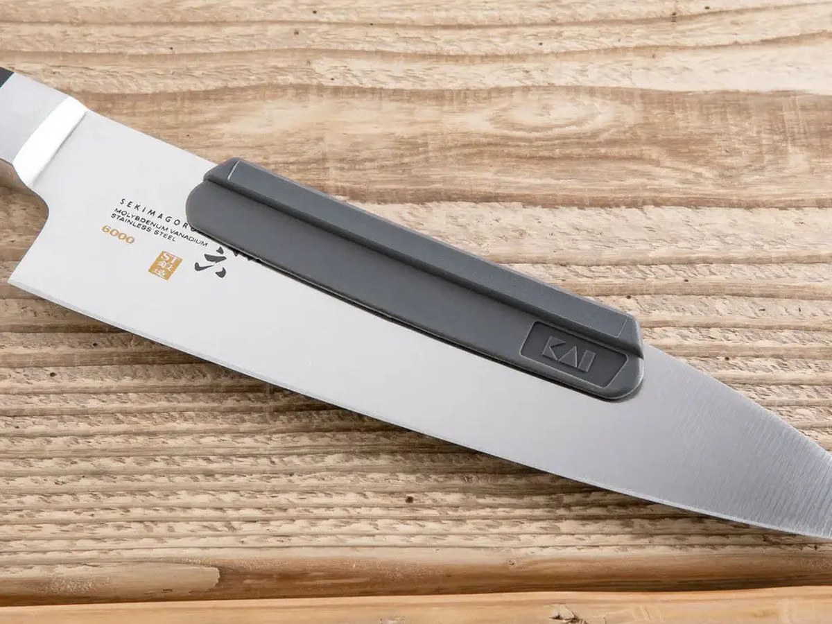 A leather knife roll, blade guard and whetstone laid out beside a chef's knife