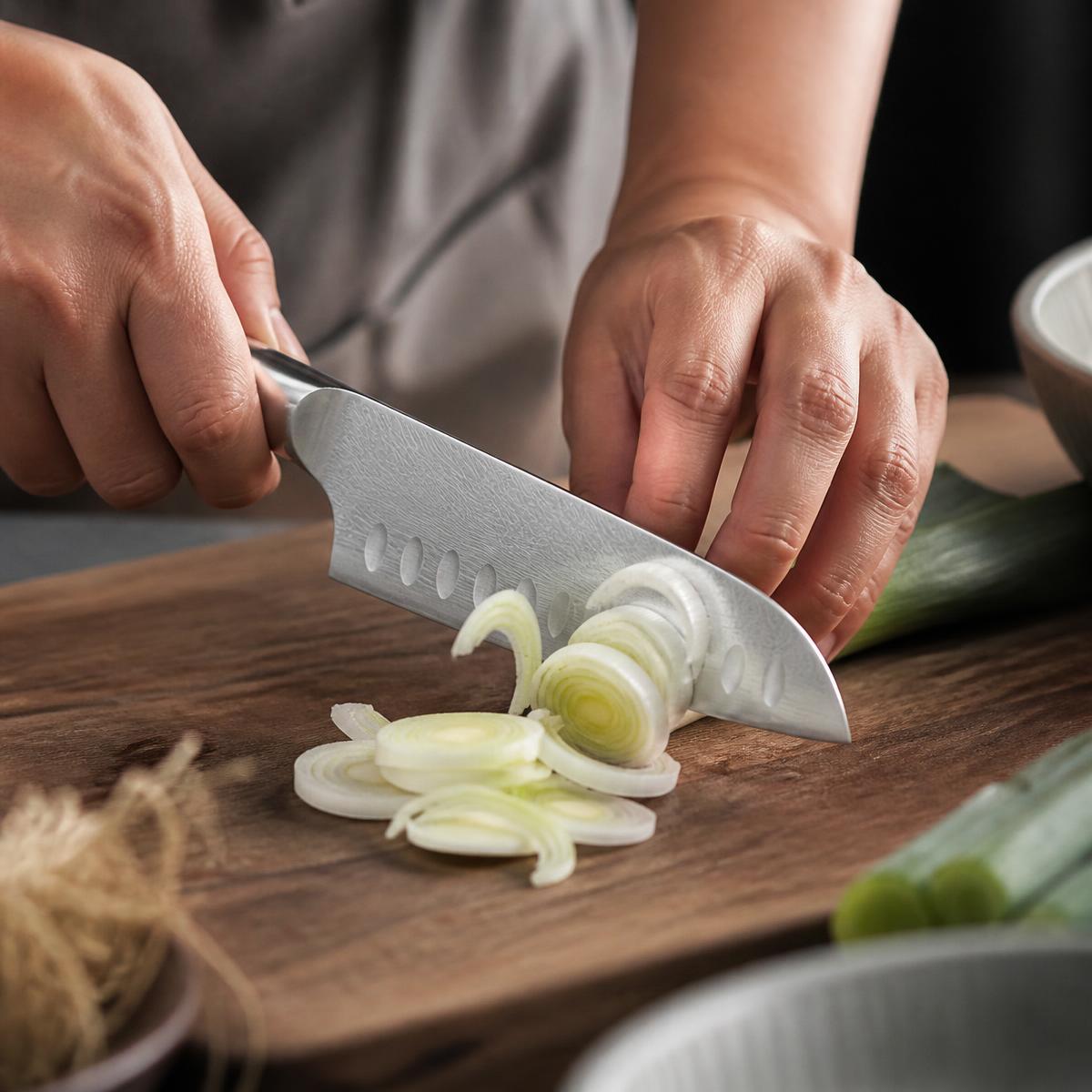 A Japanese Santoku knife finely slicing spring onions