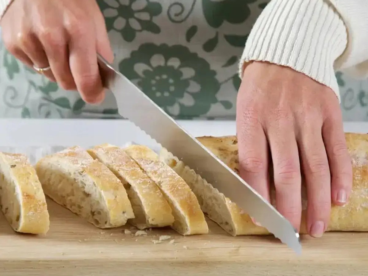 A serrated bread knife slicing a crusty sourdough loaf