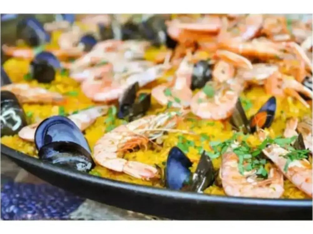 Seafood paella with prawns and mussels cooking in a Garcima Spanish enamel paella pan
