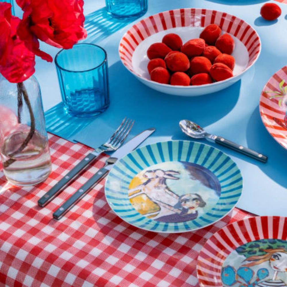 Colorful ceramic dinnerware on a picnic table with red checkered cloth and blue glasses