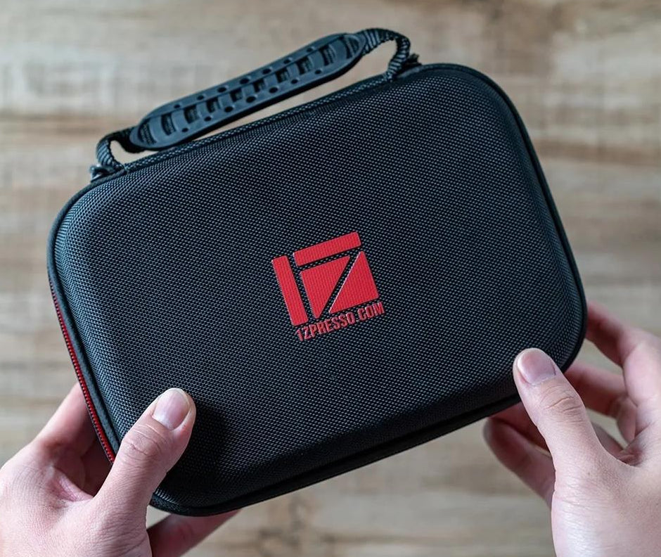 Black carrying case with red logo held by hands on a wooden surface