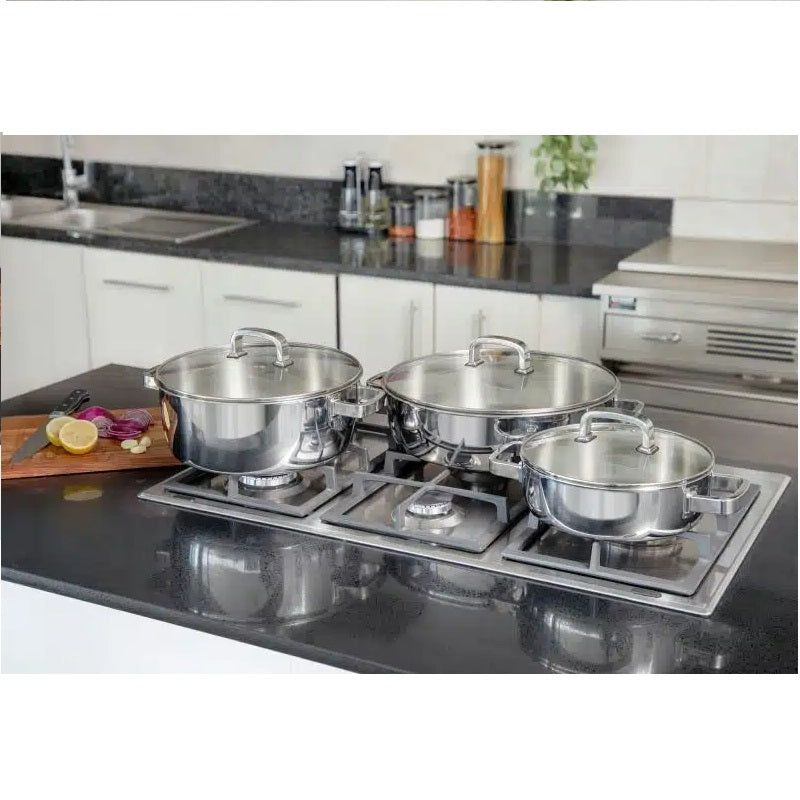 Set of stainless steel pots and pans on a kitchen stove with a modern kitchen background.
