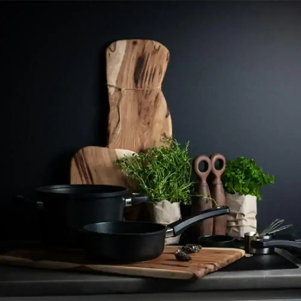 Black cookware set on a wooden cutting board with a dark background