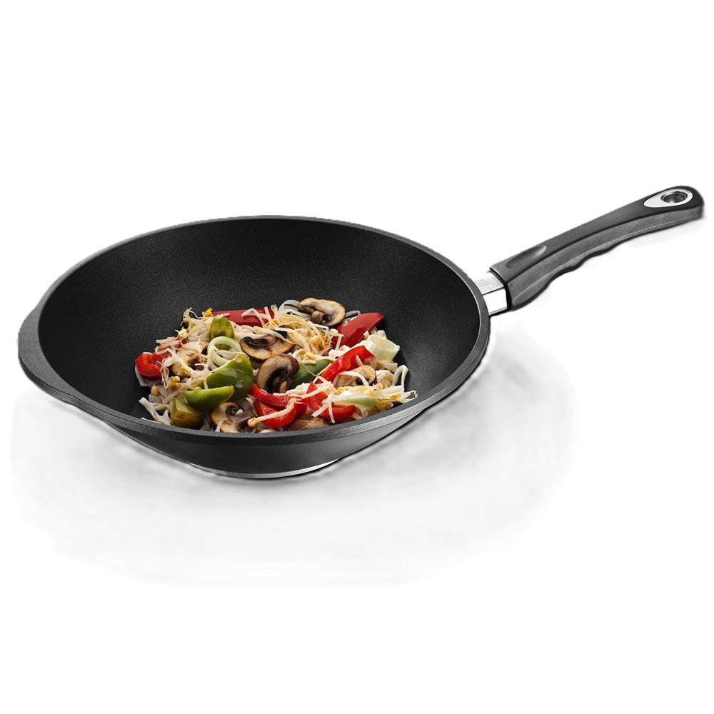 Black wok with stir fried vegetables on a white background 