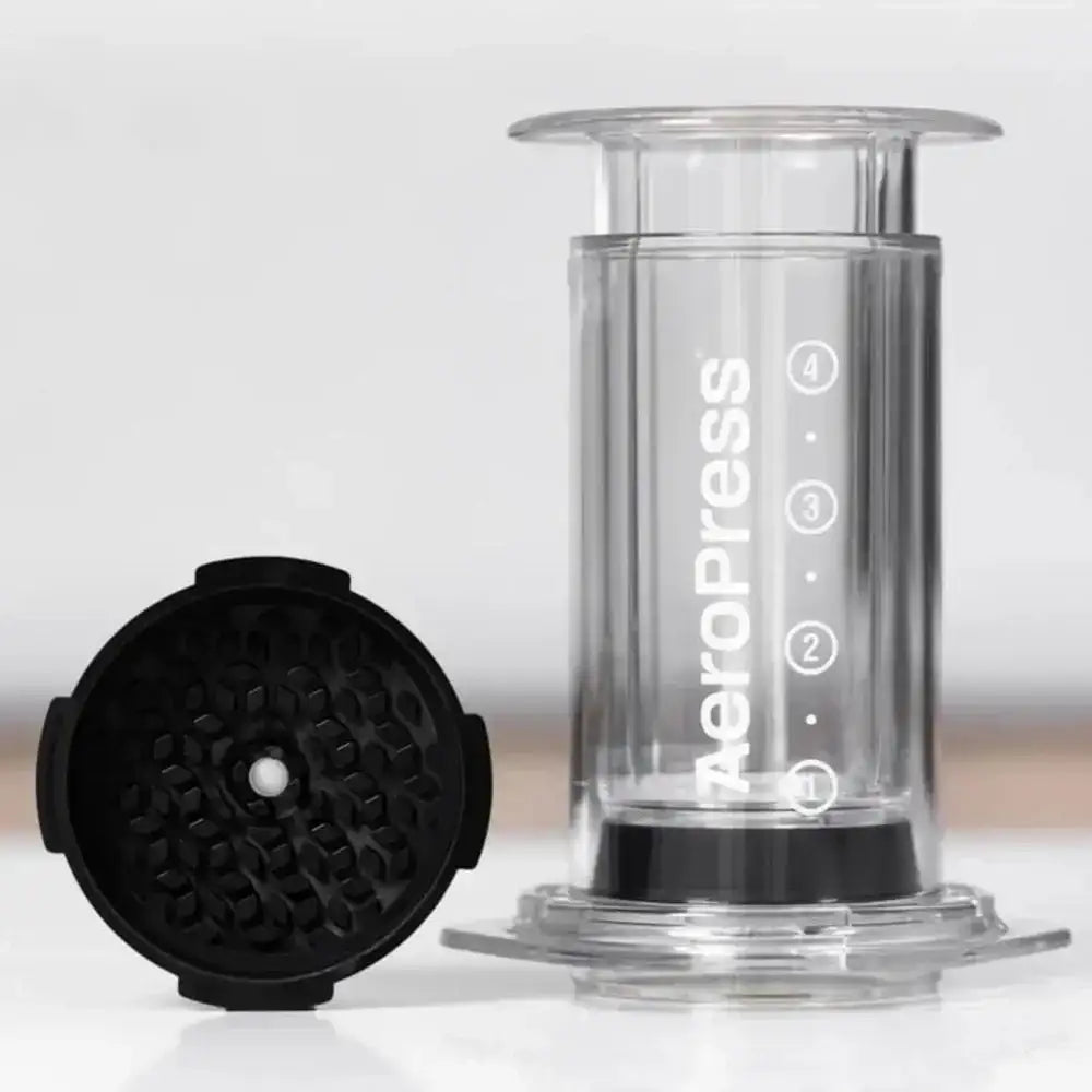 Aeropress coffee maker with clear chamber and black lid on a white background