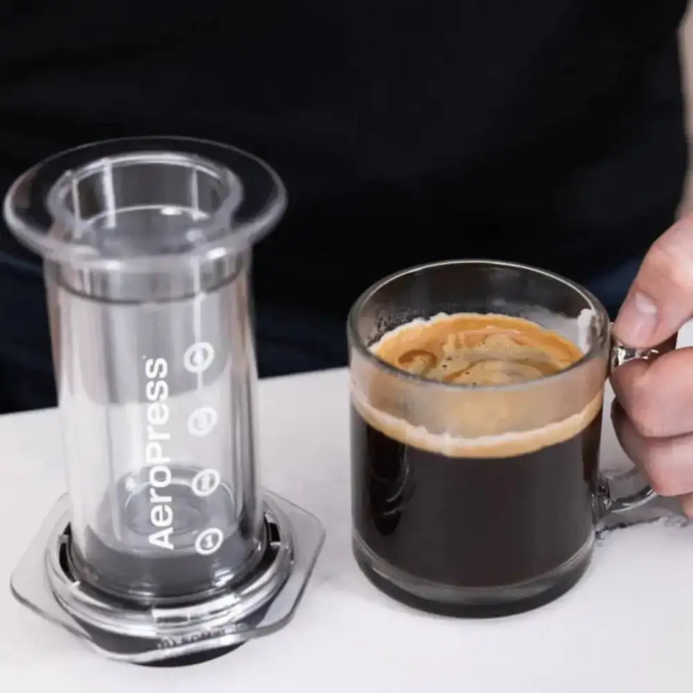 AeroPress Flow Control Filter Cap with fresh espresso in glass mug on kitchen counter