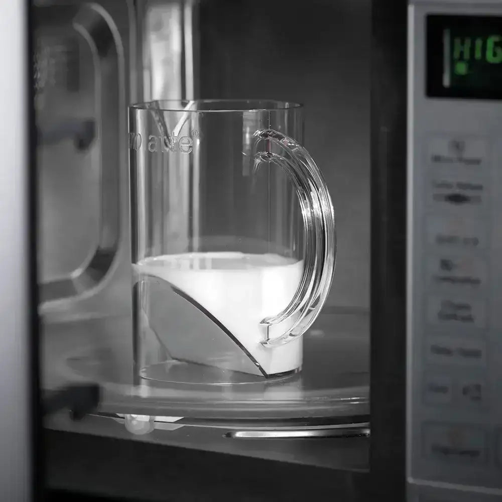 Clear glass pitcher with handle inside a microwave oven