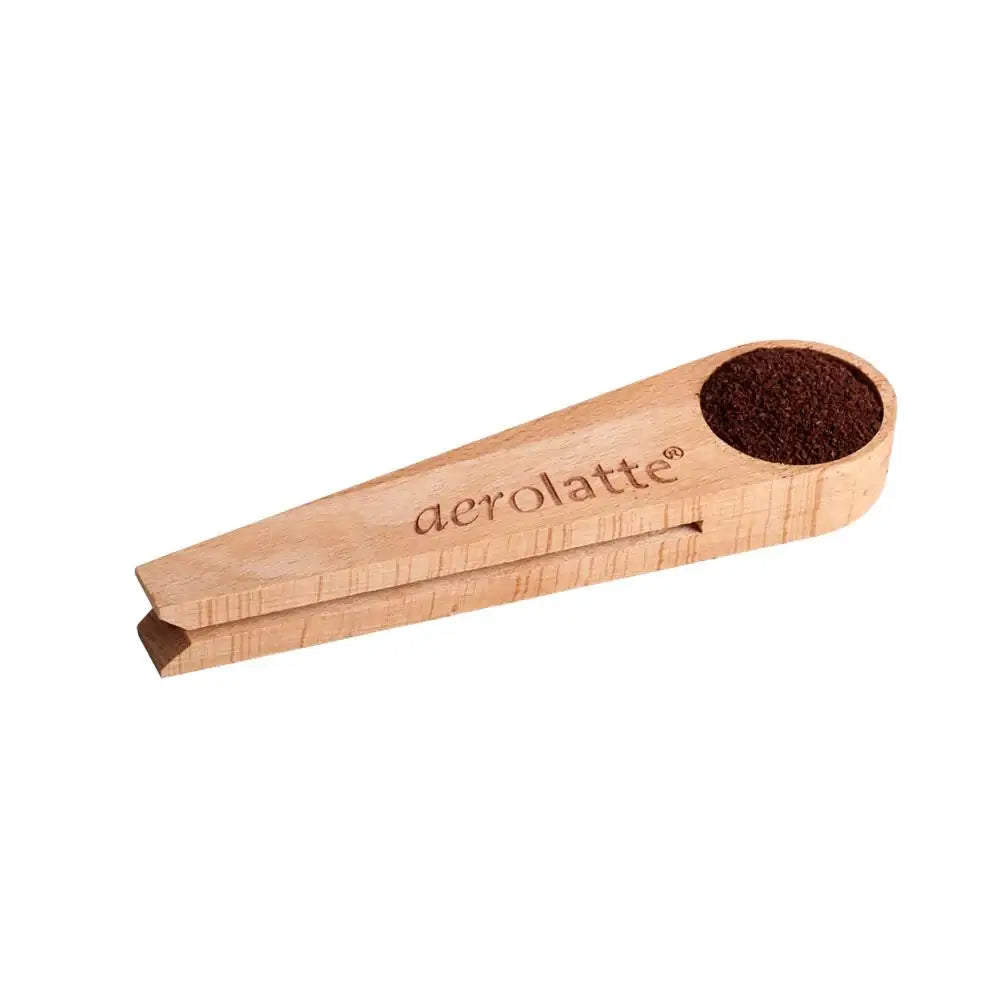 Wooden coffee scoop with ground coffee on a white background, branded 'aerolatte'.