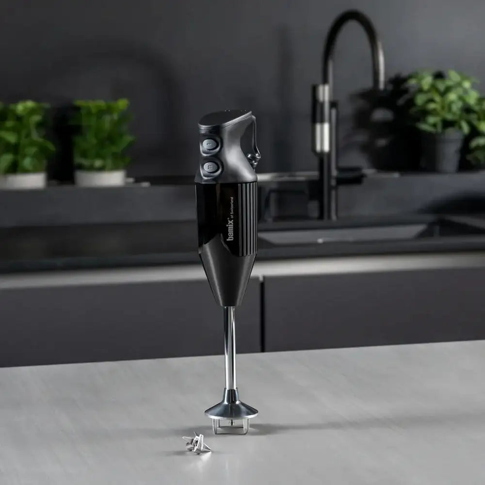 Black immersion blender on a kitchen counter with a blurred background