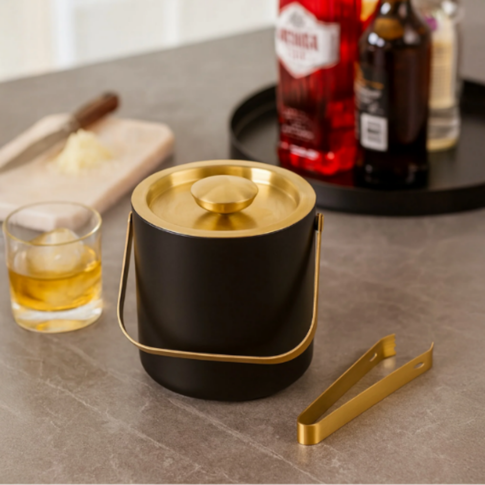Black ice bucket with gold lid and handle on a table with drinks and ice.