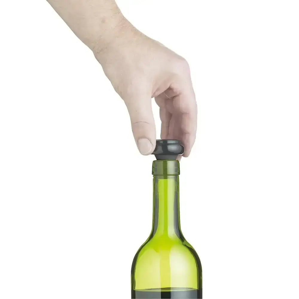 Hand using a bottle stopper on a green wine bottle against a white background