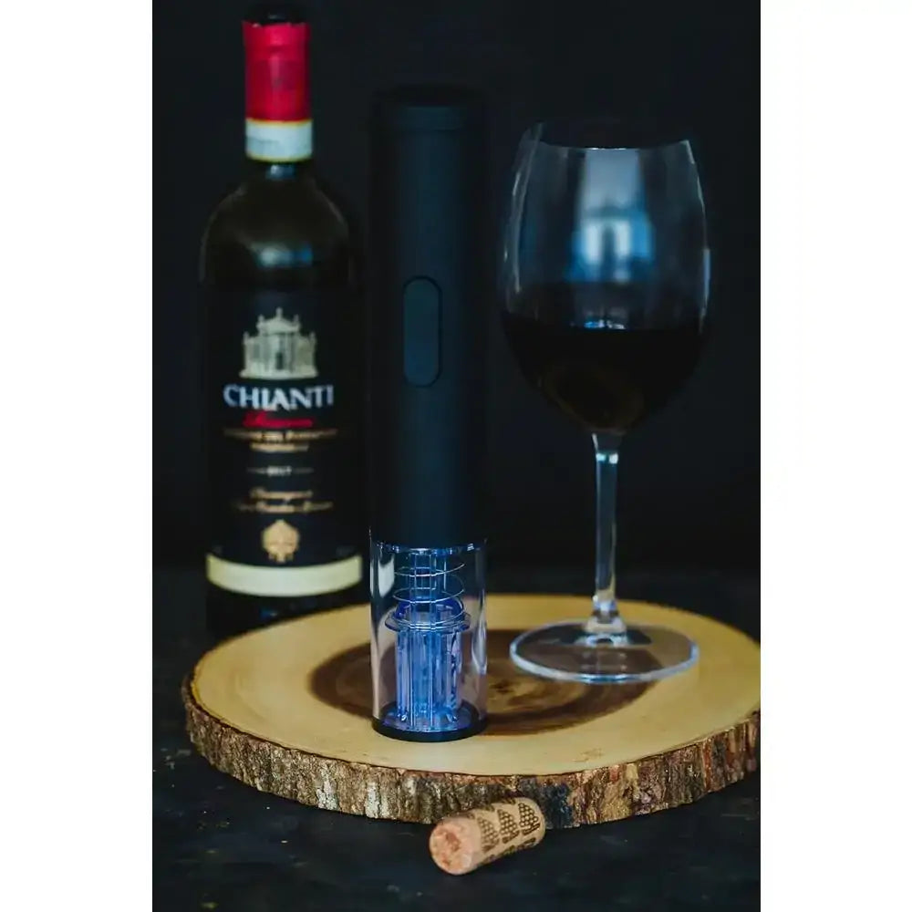 Chianti wine bottle, wine glass, and electric wine opener on a wooden board with a dark background.