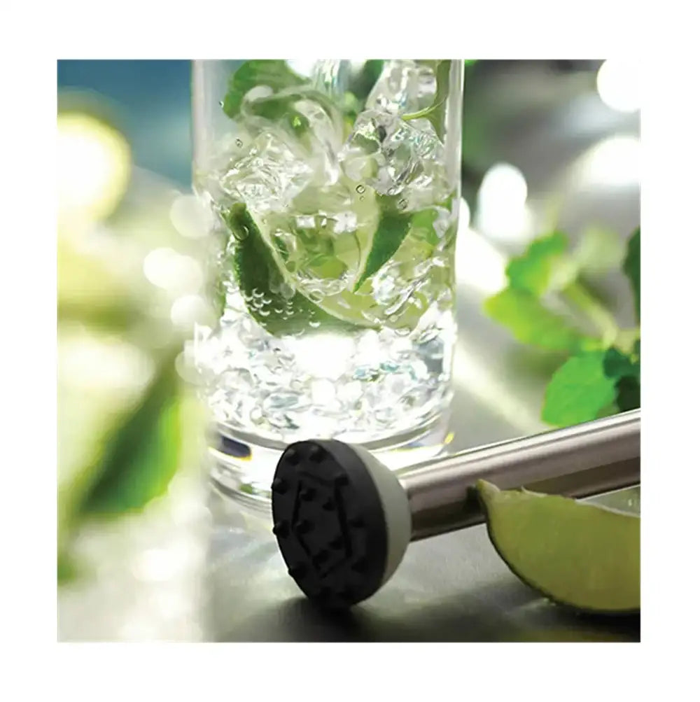 Clear glass with ice and lime, cocktail stirrer with black handle, blurred green background