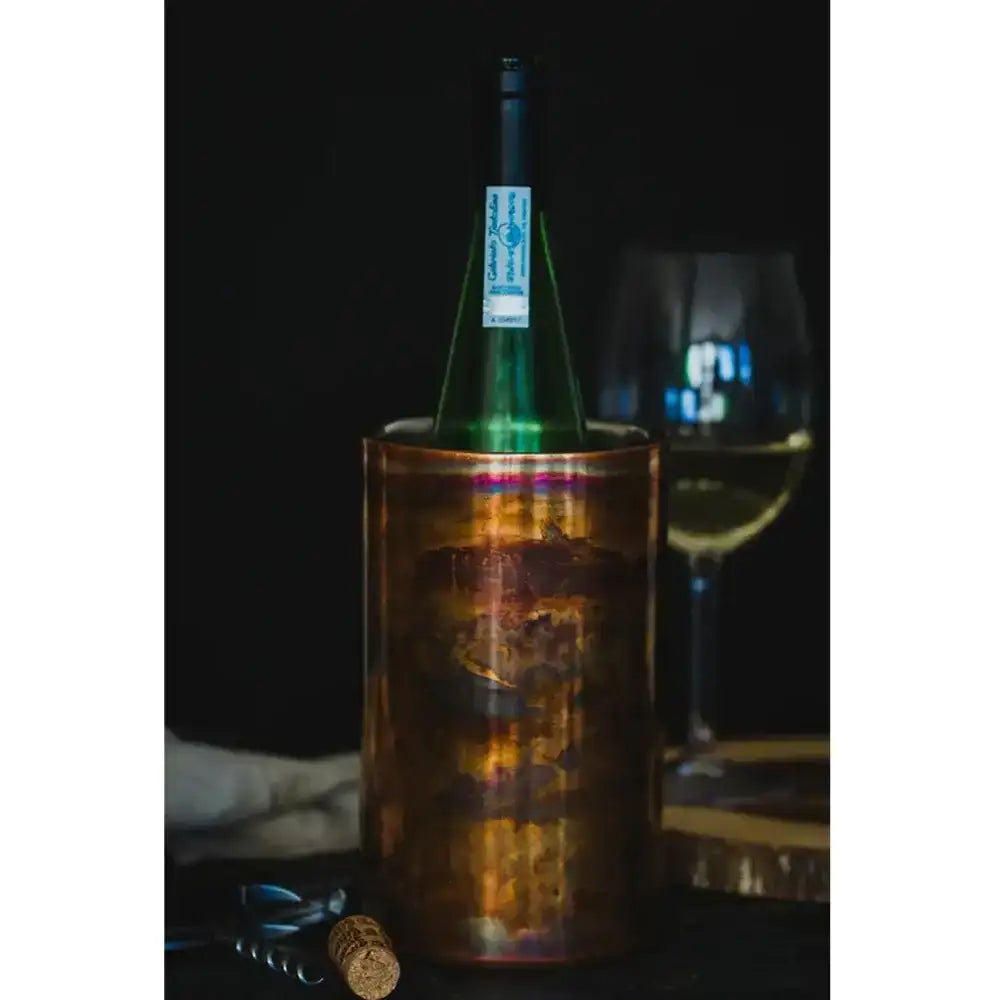 Wine bottle in a decorative holder with a glass of wine in the background