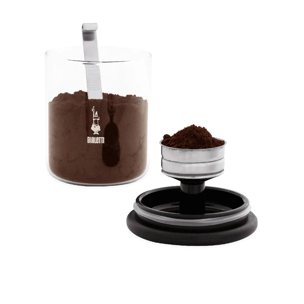 Coffee grinder with a clear container of ground coffee and a scoop on a white background