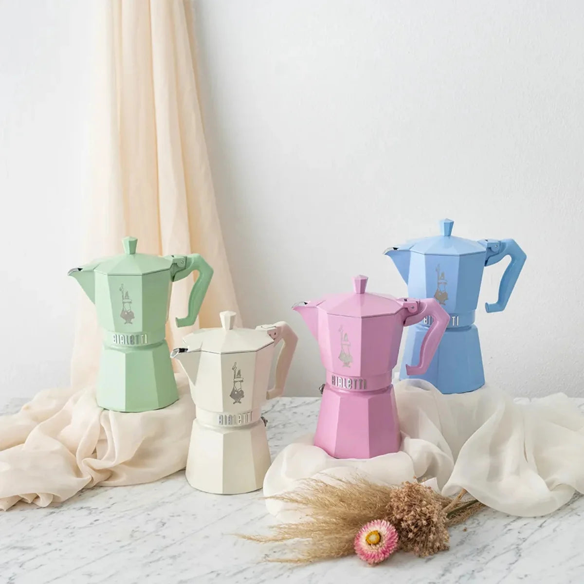 Four colorful Bialetti coffee makers on a light surface with a soft background