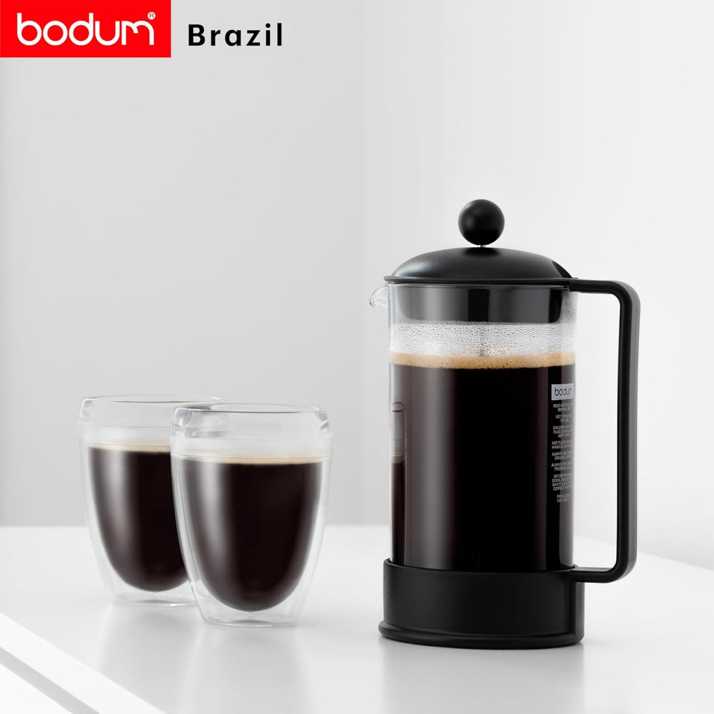 A bodum French press coffee maker in black with a clear glass carafe, shown alongside two double-walled glass cups filled with black coffee on a white surface against a light gray background.