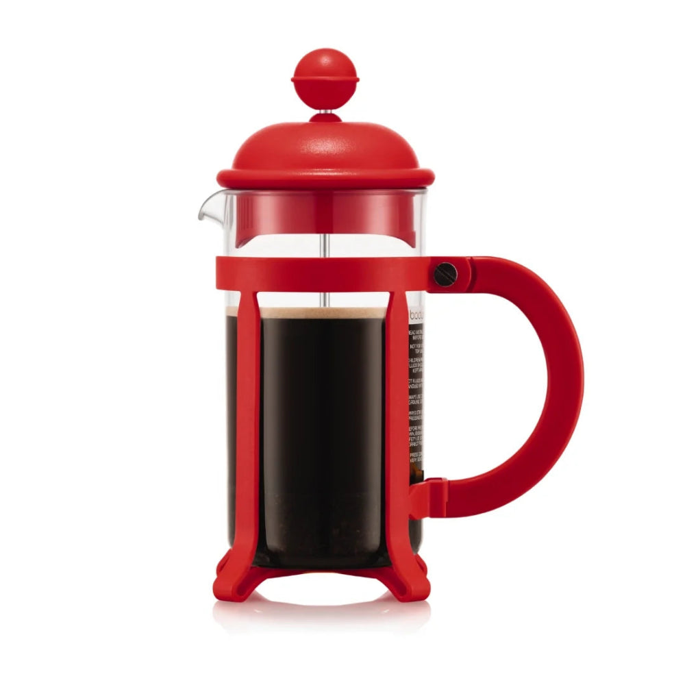 A classic French press coffee maker with a bright red plastic frame, lid, and handle, filled with black coffee in a clear glass carafe, shown on a white background.