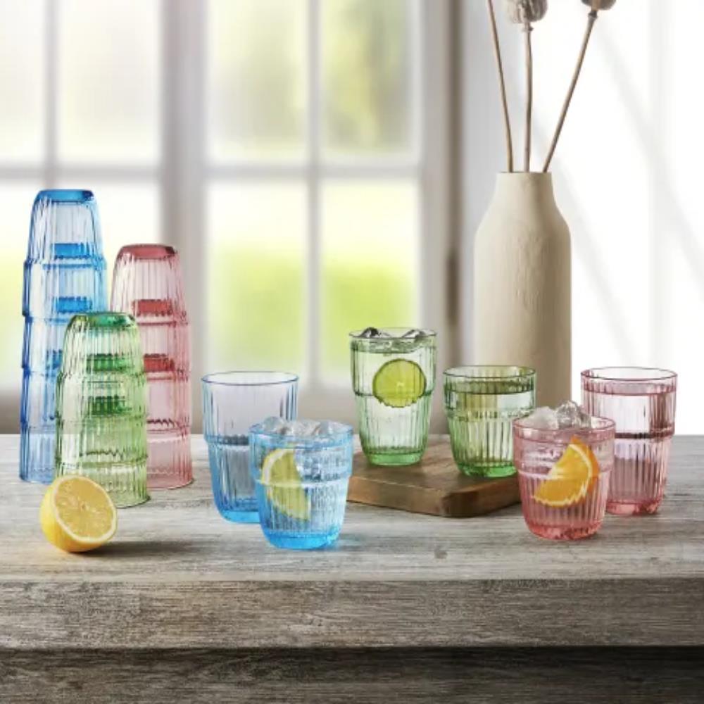 Set of colorful glass tumblers on a wooden surface with lemons and limes.