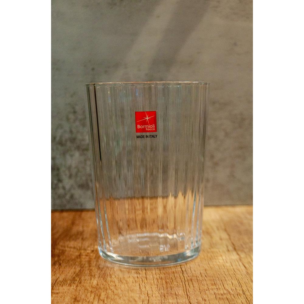 Clear glass vase with a brand logo on a wooden surface and textured wall background