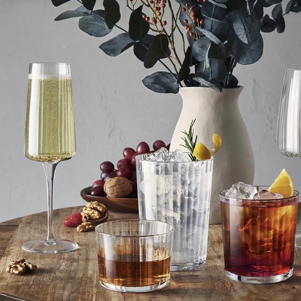 Assorted drinks in glasses on a wooden table with a vase of eucalyptus in the background.