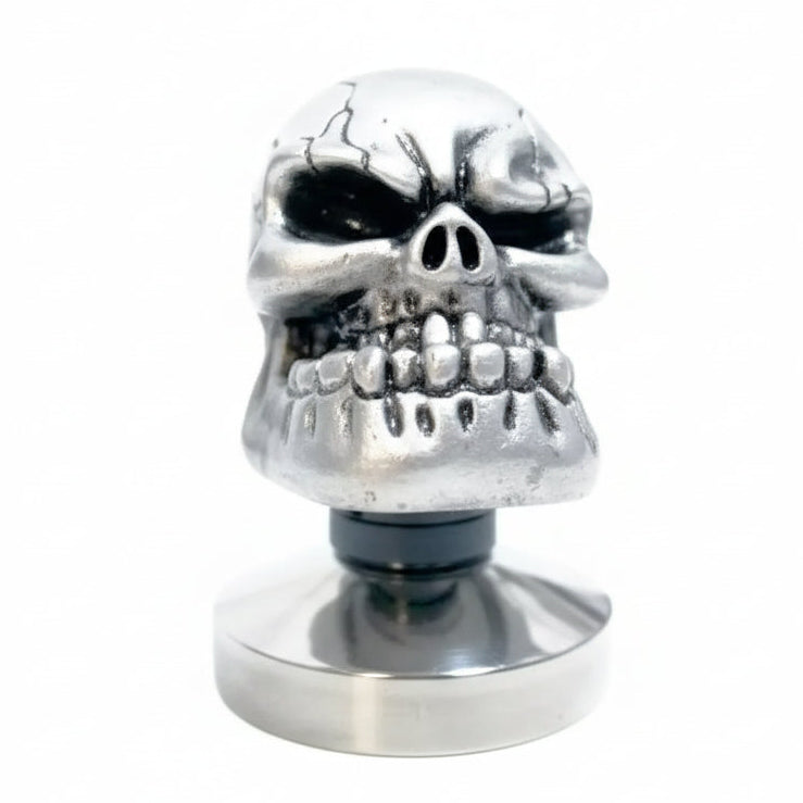 Metallic skull-shaped tamper on a white background