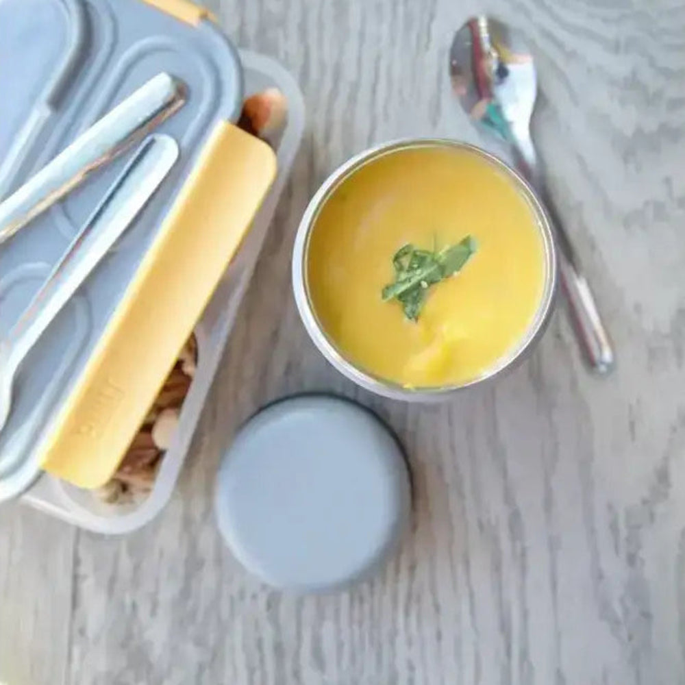 Yellow bowl with a spoon on a marble surface