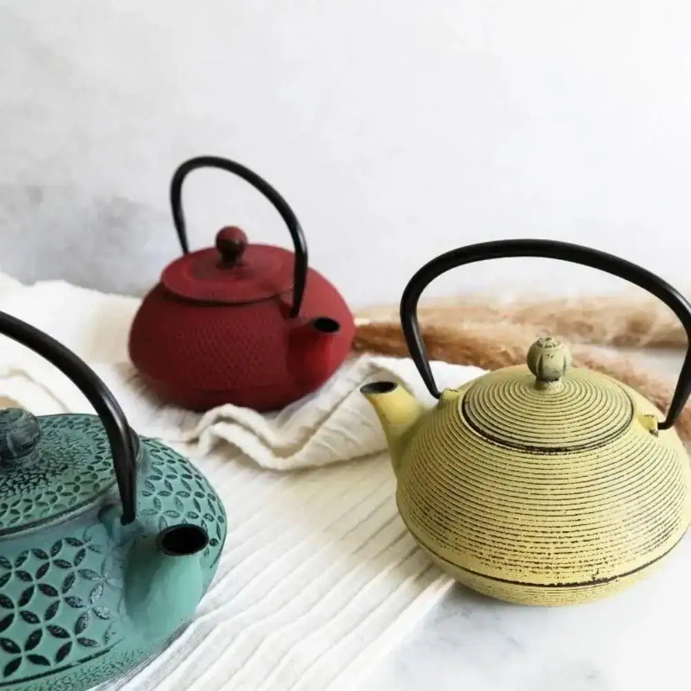 Four colorful teapots on a white surface with a light gray background