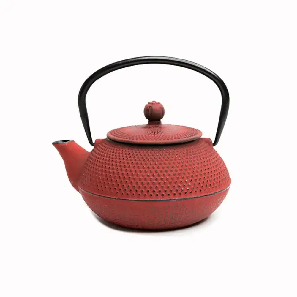 Red cast iron teapot with black handle on a white background