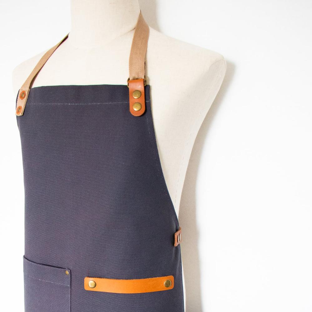 Charcoal Navy apron with brown leather straps and accents on a mannequin against a white background