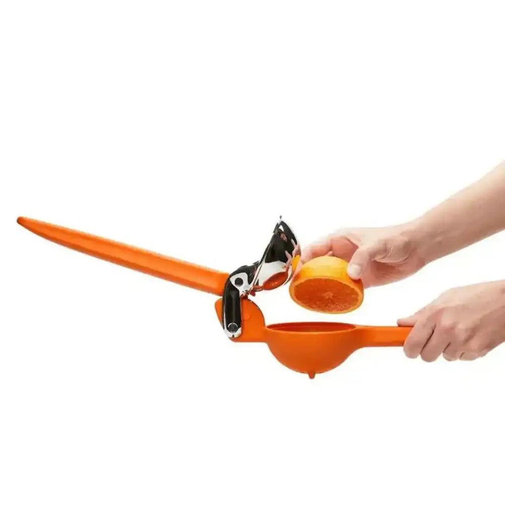 Orange manual juicer being used to extract juice from an orange on a white background