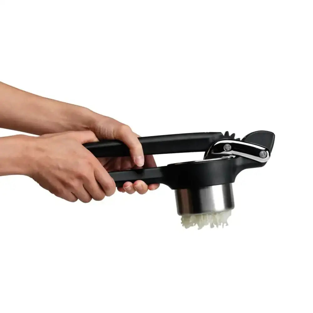 Person using a garlic press on a white background