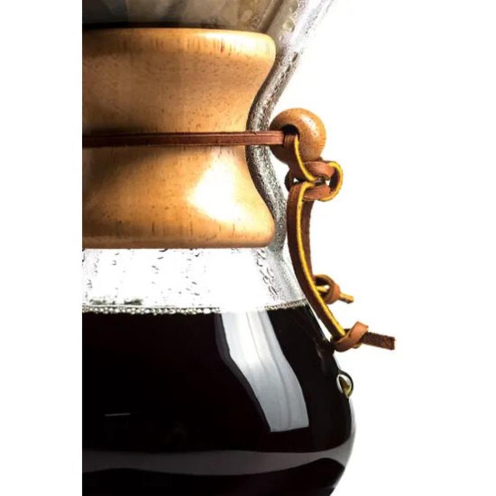 Close-up of a bronze and glass coffee maker with coffee being brewed.