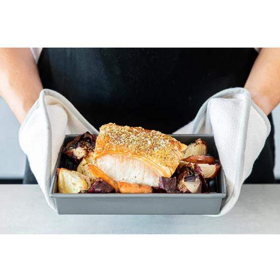 Chicago Metallic baking and roasting pan with cooked meat and vegetables, held with tea towels