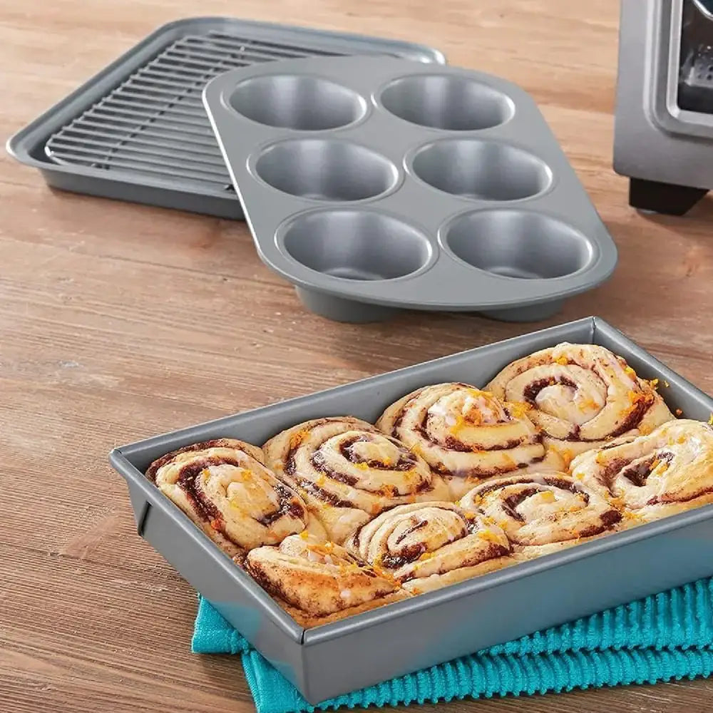Chicago Metallic non-stick bakeware set with cinnamon rolls, muffin pan, cooling rack on wood table
