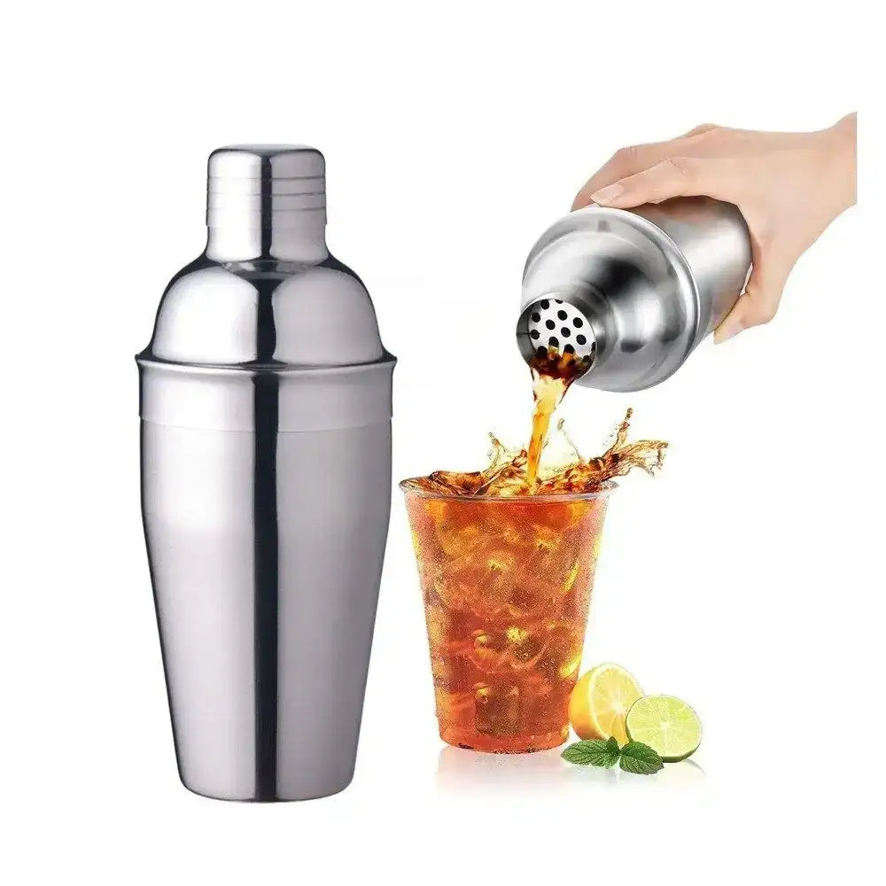 Silver cocktail shaker being used to pour a drink into a glass with ice and garnishes on a white background.