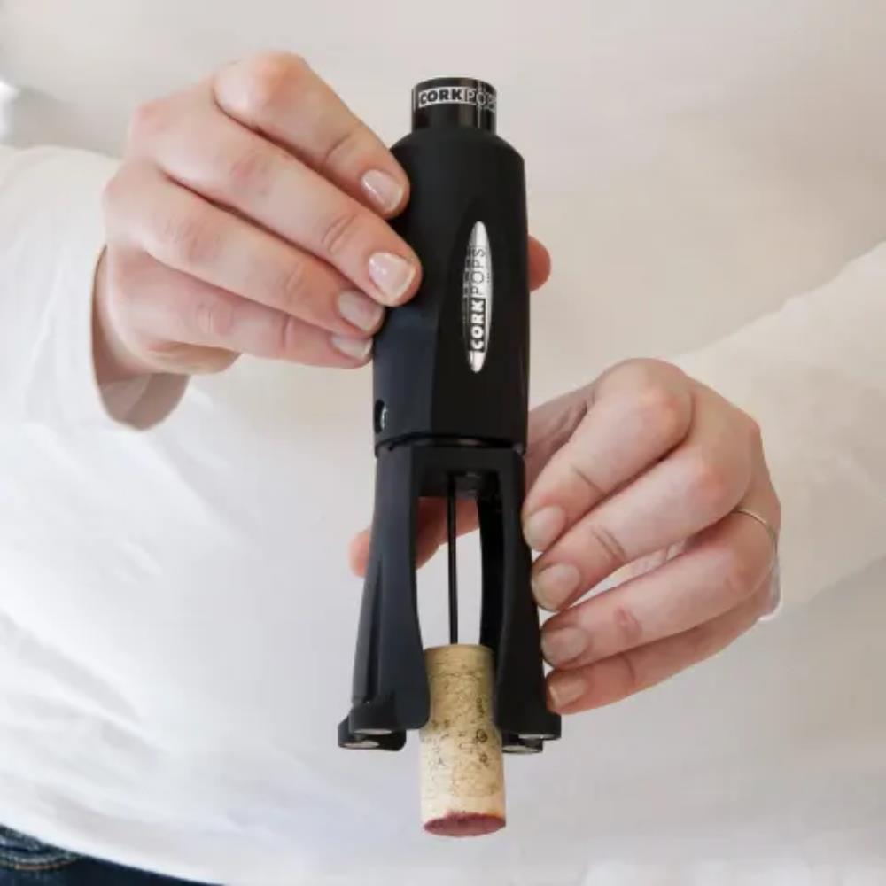 Person using a black corkscrew to remove a cork from a bottle.