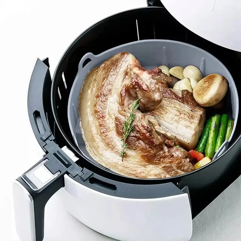 Meat and vegetables in an air fryer basket on a white background 