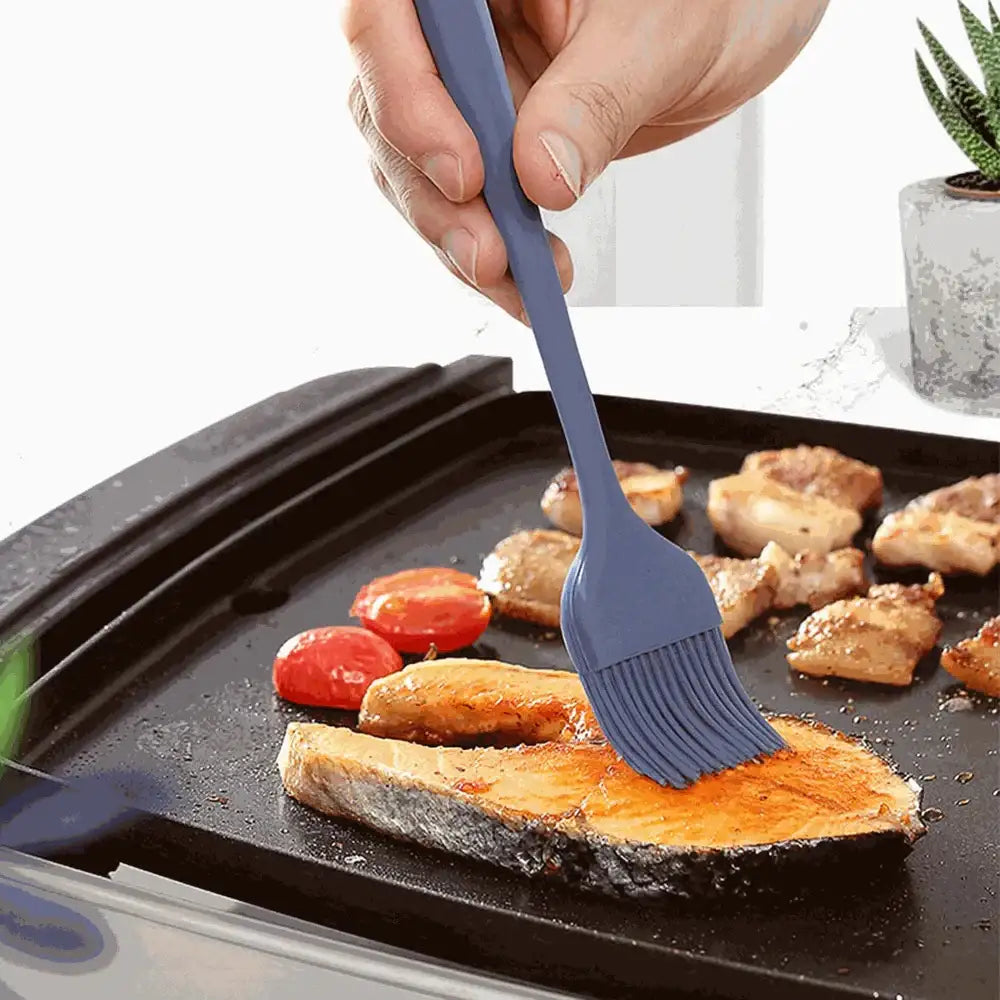 Person using a silicone brush to apply sauce on food on a grill