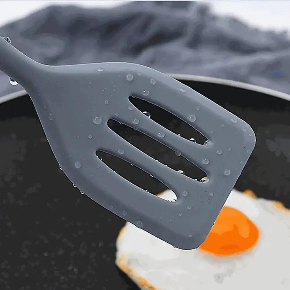Gray silicone spatula over a fried egg on a pan