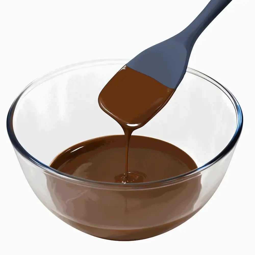 Glass bowl with melted chocolate and a gray spatula