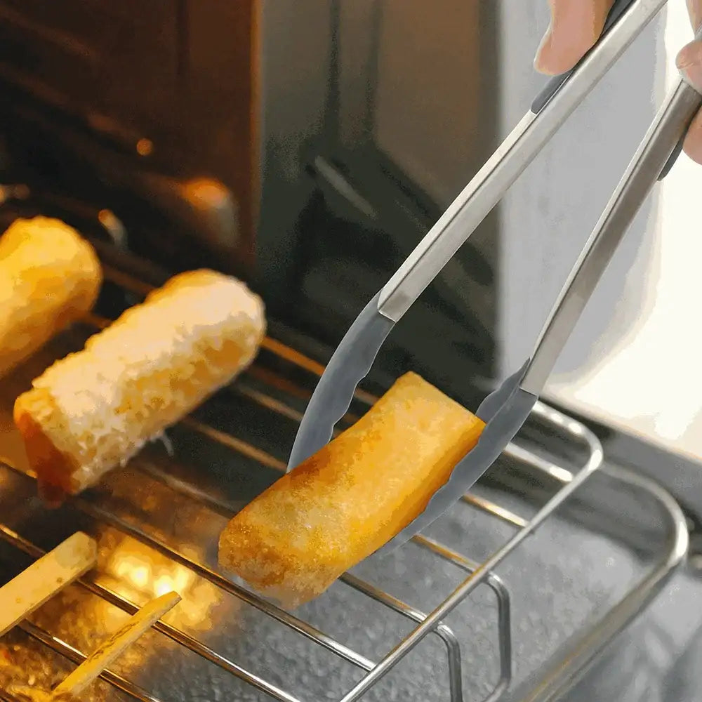 Person using tongs to remove a golden-brown food item from an oven.