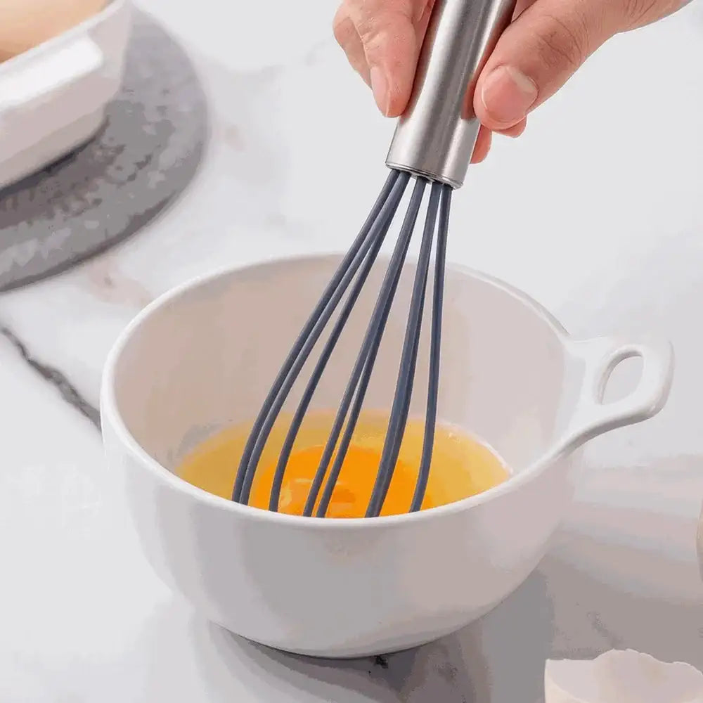 Hand whisking eggs in a white bowl on a light background