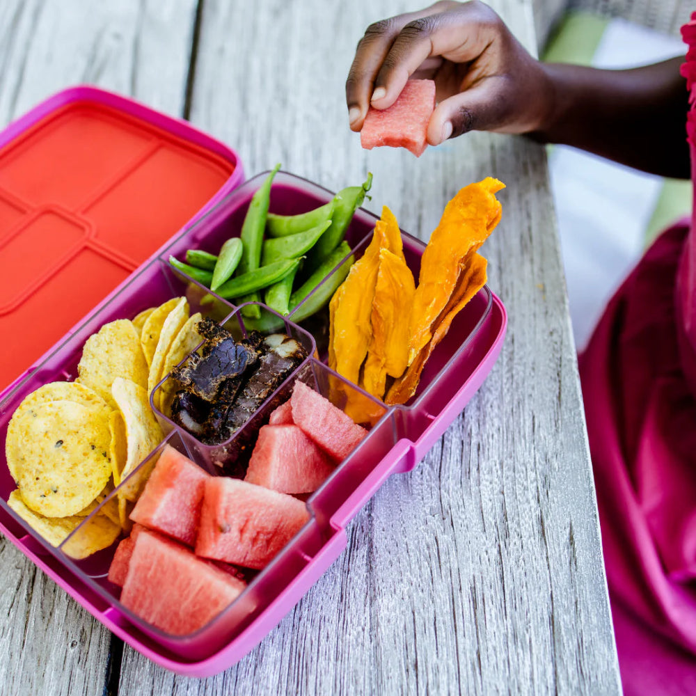 Bento style lunchbox with various types of food on a wooden surface 