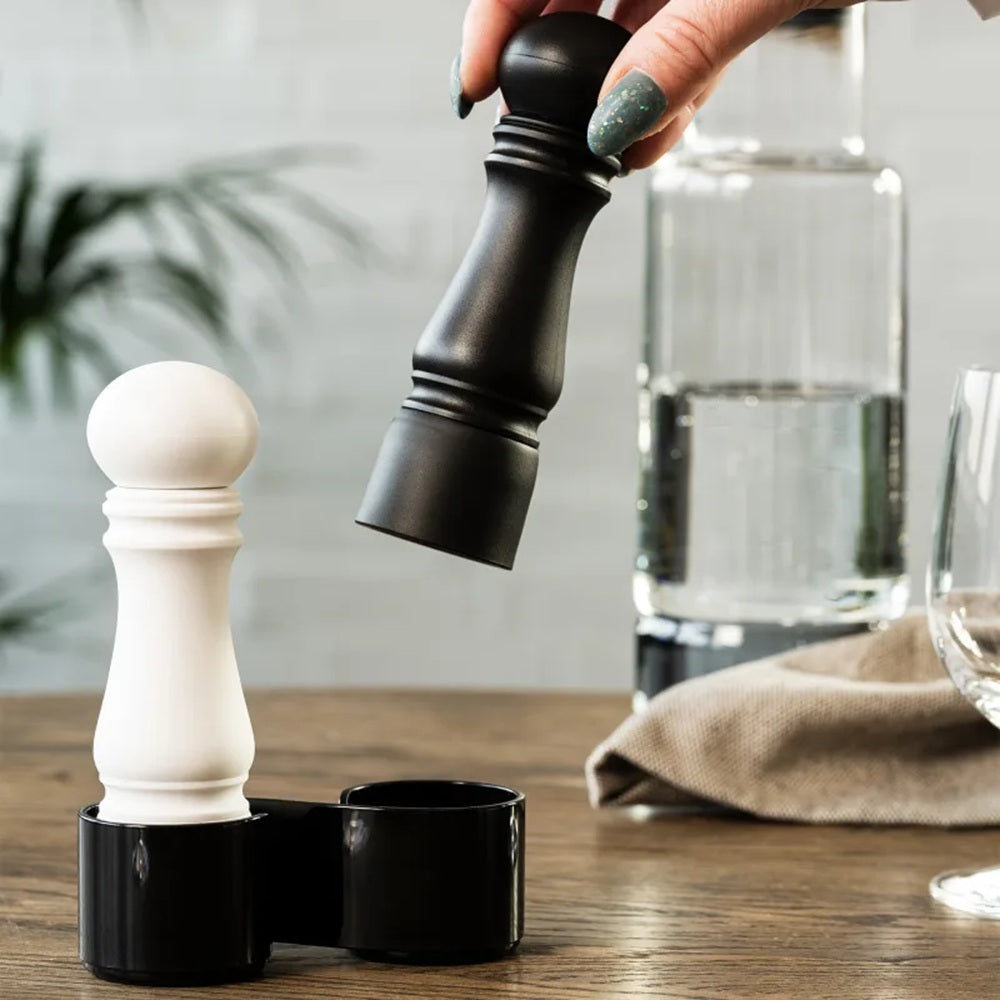 Black and white pepper grinder set on a wooden surface with a blurred background