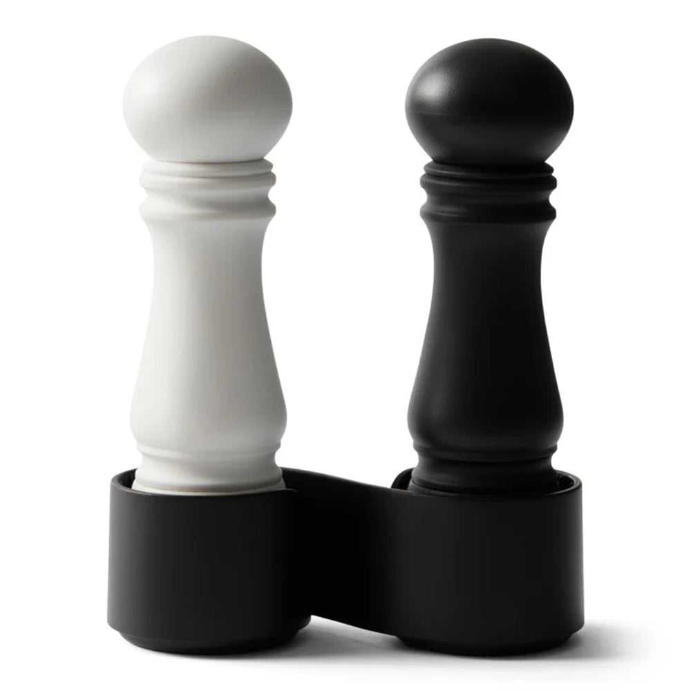 Black and white pepper grinders in a matching holder on a white background