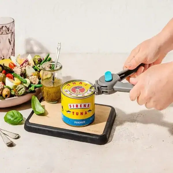 Grey Dreamfarm Dopener can opener opening a tuna can on cutting board, fresh salad nearby