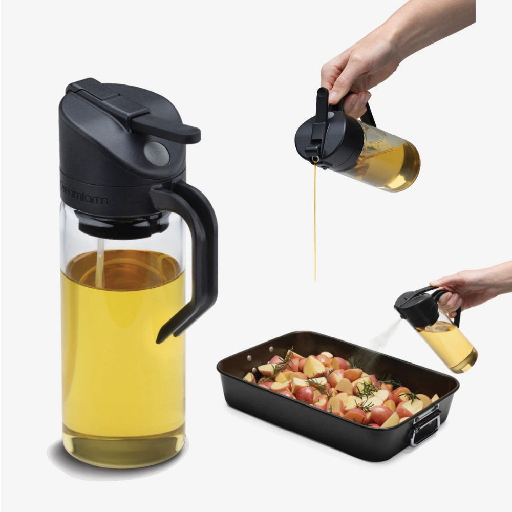 Glass oil dispenser with black cap being used to drizzle oil over roasted vegetables.